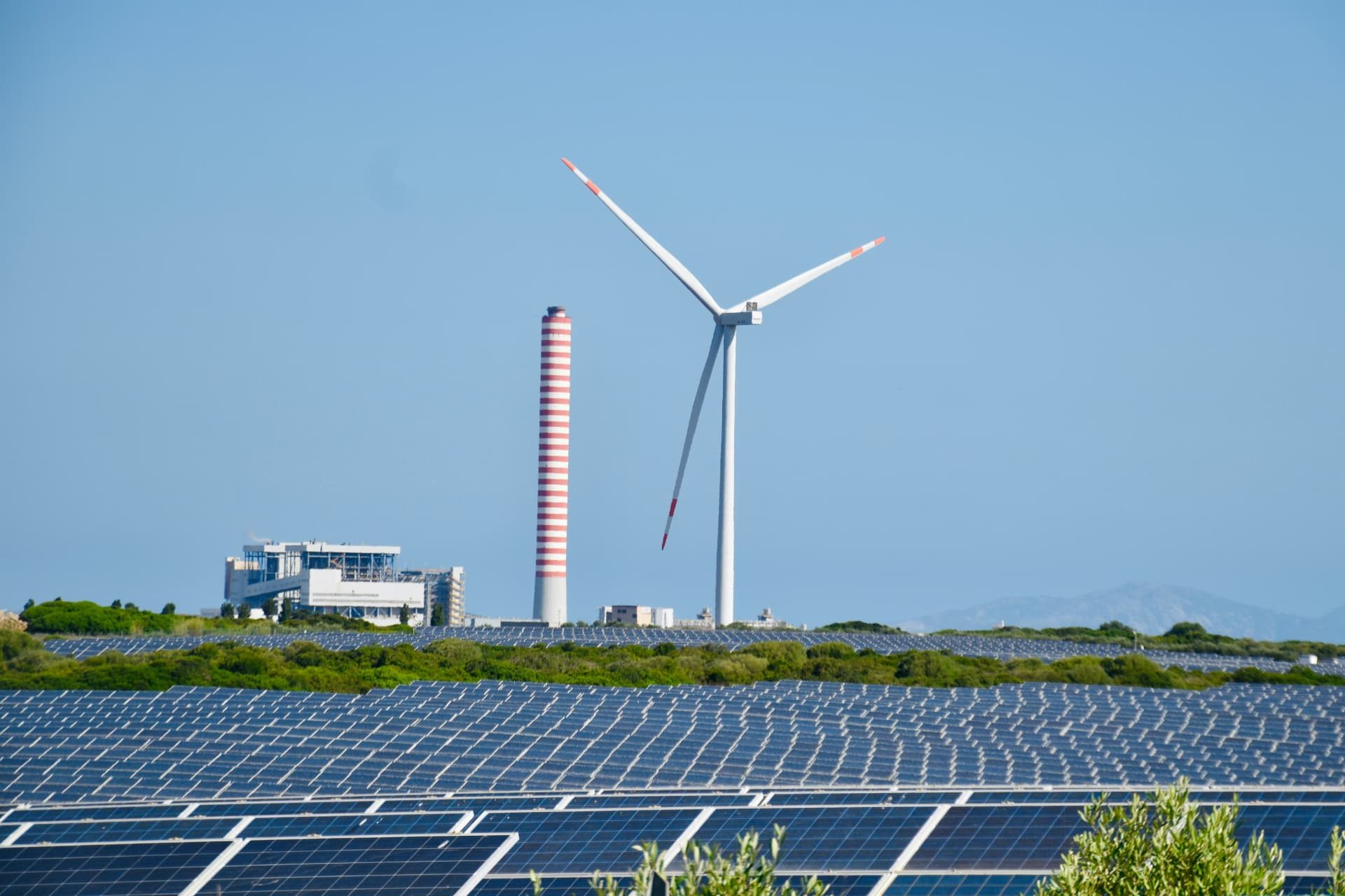 Wind turbine, solar panels and power-generation infrastructure representing a mixed energy landscape