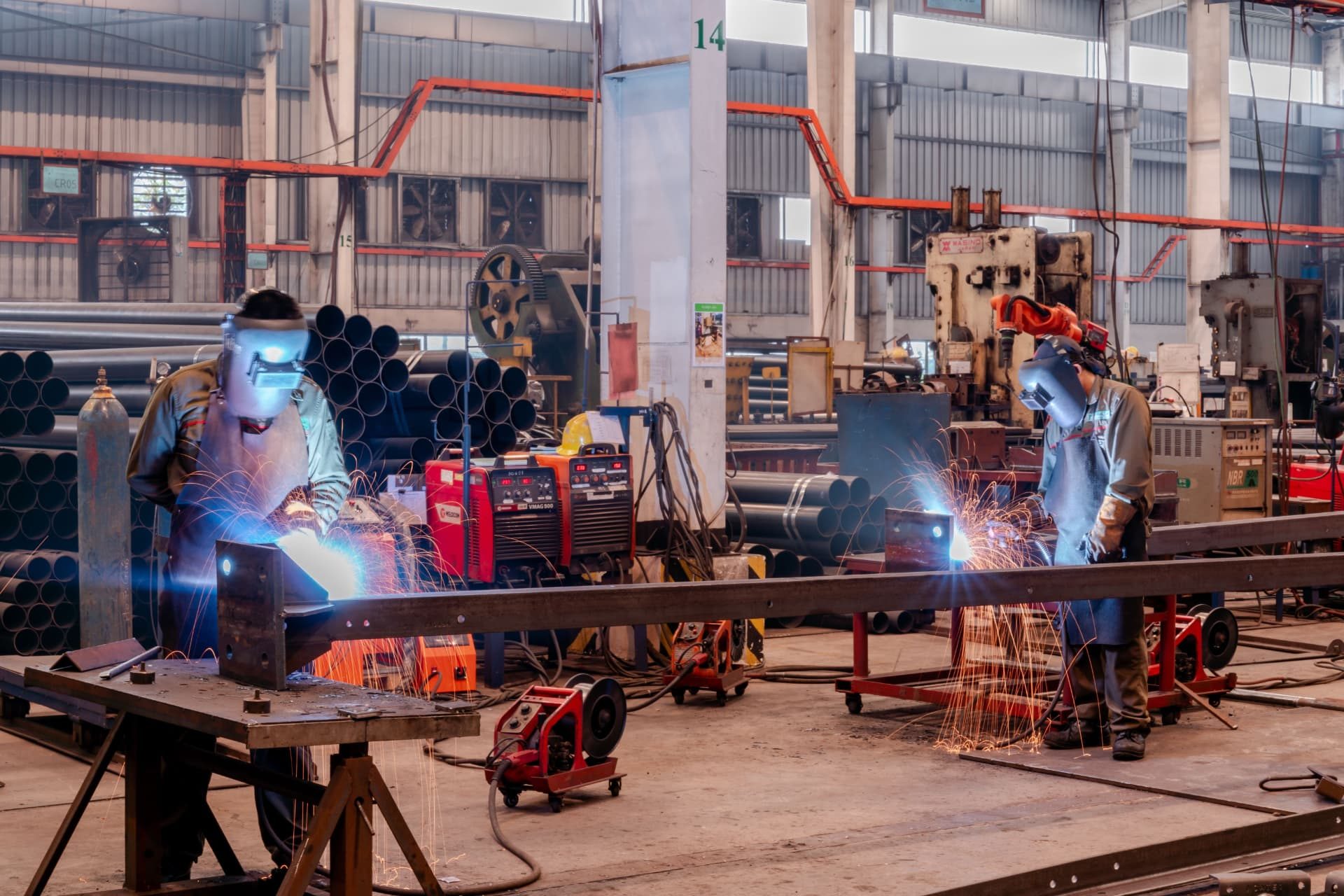 Welders fabricating steel components in an industrial manufacturing workshop