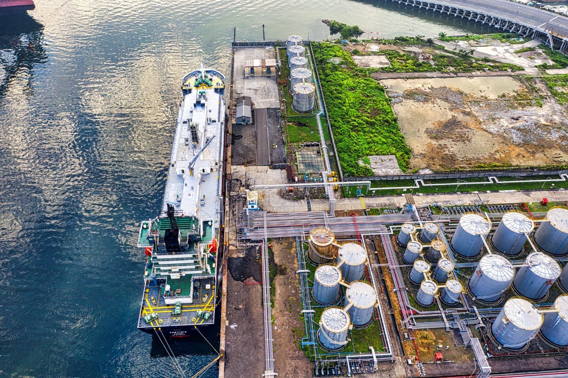 Marine industrial terminal with storage tanks, pipework and a vessel alongside