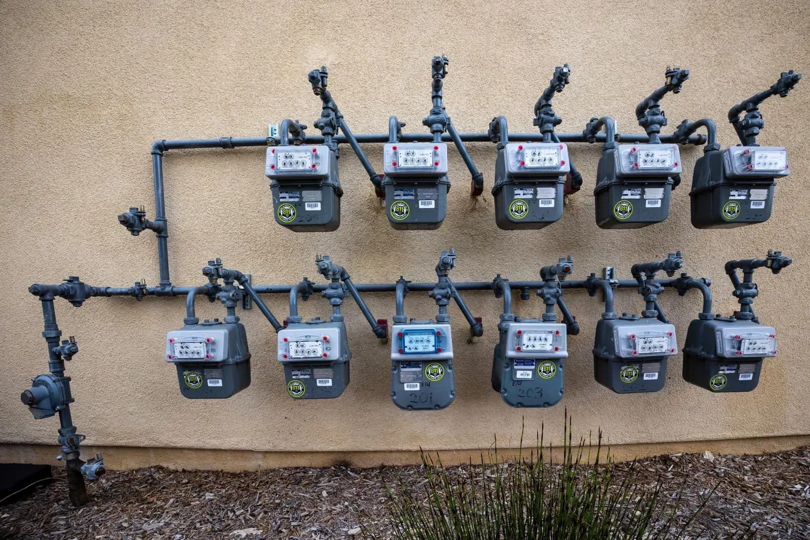 Utility gas meters and distribution pipework installed on an external wall
